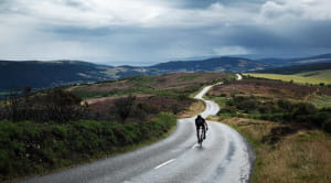 person cycling on road in countryside